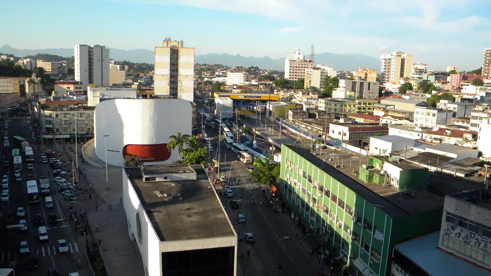 Praça do Pacificador, no centro de Duque de Caxias, com o Teatro Raul Cortez e a serra ao fundo, na página de contabilidade em Duque de Caxias